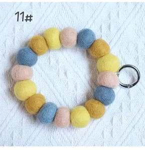 Macro detail of handmade wool felt ball keychain with a silver spring ring buckle