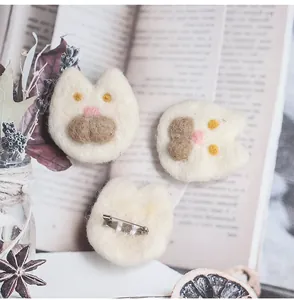 Detail of cute handmade wool felt cat brooch on a vintage book background