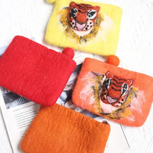 Handmade wool felt tiger face coin purses in vibrant orange and red on lace background
