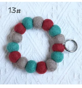 Close-up of handmade felt ball charm with red grey cyan wool spheres and silver ring