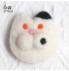 Macro view of handmade white cat wool felt brooch with orange eyes and textured finish