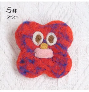 Close-up of a red wool felt cartoon monster brooch showing 5x5cm size and fuzzy texture