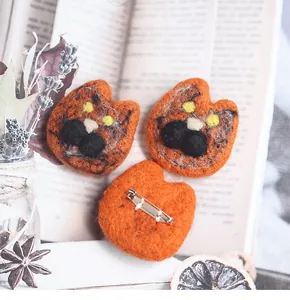Detail showing the silver metal pin fastener on the back of the orange wool felt cat brooch