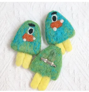 Detailed view of handmade wool felt brooches with metal safety pin backing on fabric