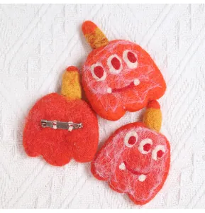 Detailed view of handmade wool felt monster brooches with secure metal pin backings