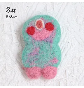 Detailed macro of handmade green wool felt monster brooch showing soft fuzzy texture
