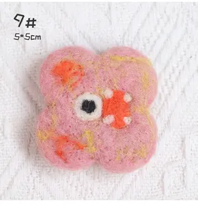 Detail of a 5x5cm pink handmade felt flower brooch with a unique cartoon eye design