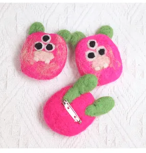 Detail of wool felt monster brooches showing handmade texture and metal pin fastener