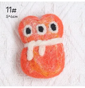 Detail of wool felt monster brooch No. 11 with three eyes and white ribbon, 5x6cm size
