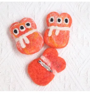 Detailed view of handmade orange wool felt pins with three eyes and secure metal safety clasp
