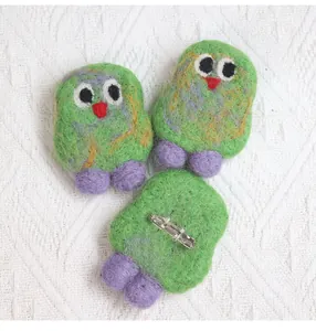 Detail view of handmade green wool felt bird brooches with silver metal safety pins