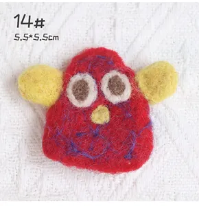 Detail shot of a red handmade wool felt monster brooch showing 5.5x5.5cm size and texture