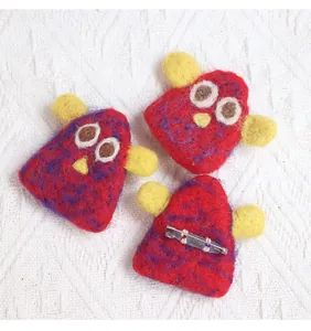 Detailed view of handmade red wool felt monster brooches with secure metal pins