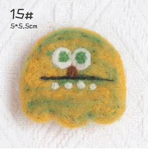 Detail shot of yellow and green wool felt monster brooch with 5x5.5cm size markings