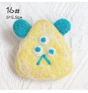 Detail of yellow wool felt monster brooch with three eyes and blue ears, 5x5.5cm size