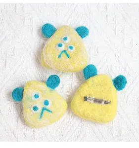 Detail of three handmade wool felt monster brooches showing texture and metal safety pins