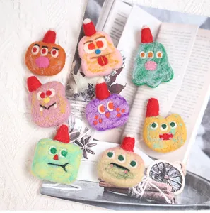 Detailed texture of handmade wool felt monsters with red hats on lace background