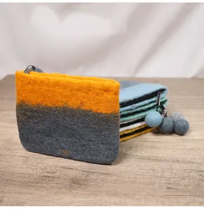 Detail view of contrast wool felt pouch with metal zipper and soft ball pendant