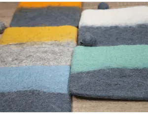 Macro shot of colorful handmade wool felt pouches showing thick fiber texture on wood