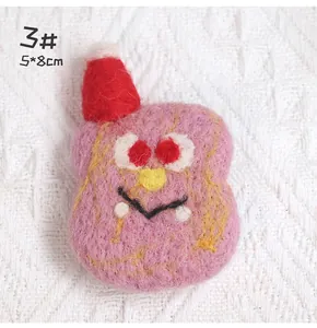 Detail of pink handmade wool felt cartoon monster brooch with red hat and 5x8cm dimension