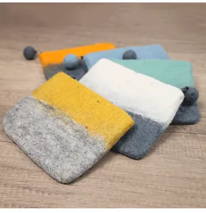 Detail view of colorful wool felt wallets with contrasting zippers on wood background
