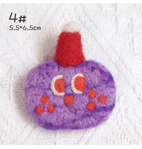 Detail shot of a purple wool felt monster pin with red hat measuring 5.5 by 6.5 cm