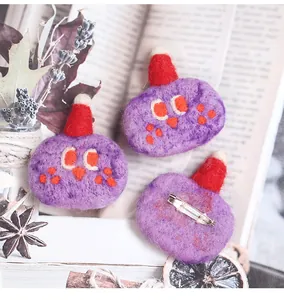 Close-up of three handmade purple felt monsters with red hats and metal brooch pins