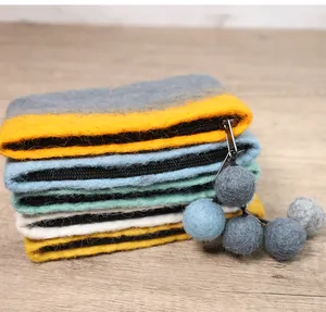 Detailed close-up of wool felt pouches with colorful pompom charms and black zippers