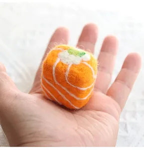 Macro detail of handmade wool felt salmon sushi charm held in palm showing realistic texture