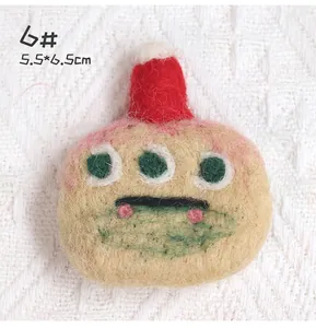 Detail shot of a handmade wool felt brooch with three eyes and red hat, size 5.5x6.5cm