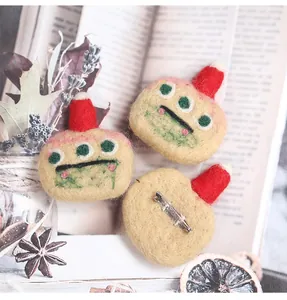 Detail of handmade wool felt brooches with red hats on vintage book pages with lavender