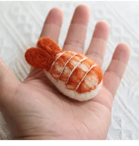 Detailed macro view of handmade wool felt sushi charm held in palm showing fuzzy texture