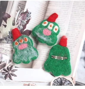 Detailed macro view showing wool felt monster pins with red hats and silver metal safety back