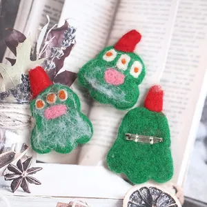 Handmade wool felt brooch set featuring green cartoon monsters and red festive hats