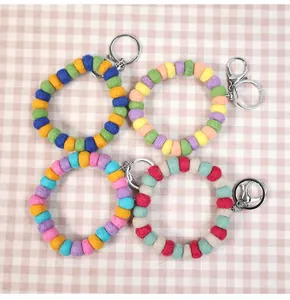 Detailed close-up of four colorful handmade wool felt ball keychains with metal lobster clasps