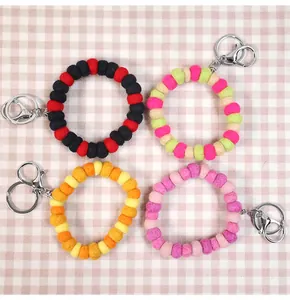 Close-up of four colorful 1cm wool felt ball keychain rings with silver metal clasps
