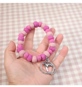Close-up of soft pink and purple wool felt ball keychain with metal clasp held in hand