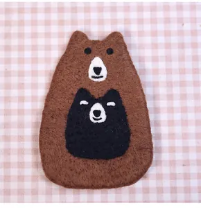 Detailed close-up of handmade brown wool felt bear coaster with needle felted texture