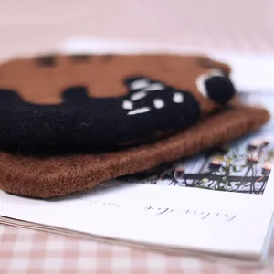 Handmade brown wool felt bear coaster on a checkered tablecloth for home decor