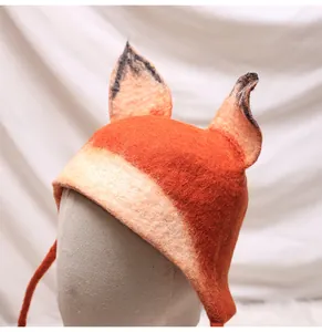 Detail of wool felt fox hat featuring handmade orange ears and long white straps