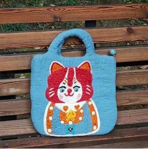 Detail of blue wool felt handbag showing textured fabric and colorful cat embroidery