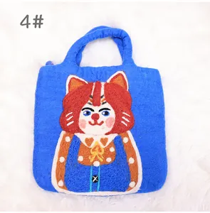 Detail of blue wool felt handbag featuring a handmade cartoon cat with needle felt pattern