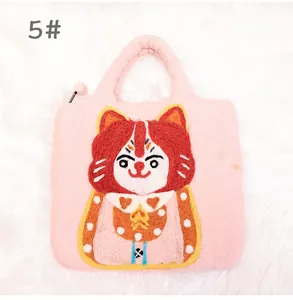 Detail of pink wool felt handbag featuring handmade cartoon cat embroidery and plush zipper pull