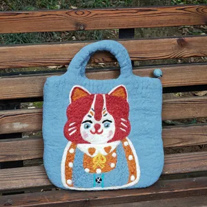 Cute blue handmade wool felt handbag featuring a unique artistic cat design on a park bench