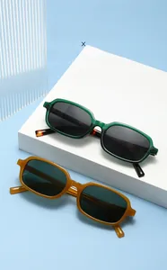 Detail view of dark green and amber square sunglasses on white geometric blocks