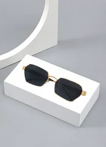 Close-up of golden octagonal geometric metal sunglasses on white pedestal display