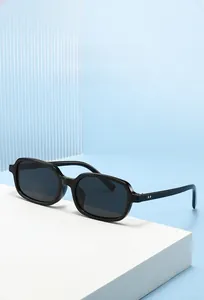 Detail of glossy black rectangular frame sunglasses featuring metallic dot rivet accents