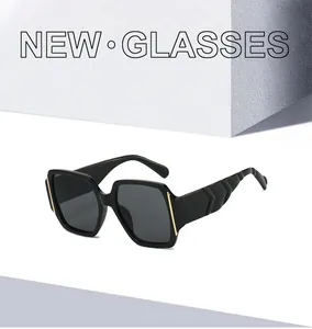 Detail of square black sunglasses featuring gold metal accents and textured wide temples