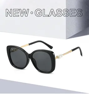 Detail of oversized black sunglasses featuring gold temples and elegant pearl accents