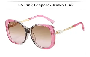 Detailed view of pink leopard sunglasses with gold metal hinges and pearl accents